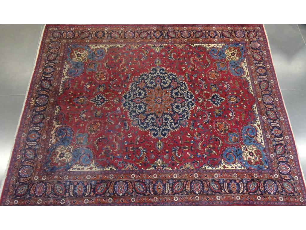 Grand tapis d'orient en laine à décor d'un grand médaillon sur fond bordeaux avec des rinceaux feuillagés. Epoque XXème siècle. Dim : 380 x 300 cm.