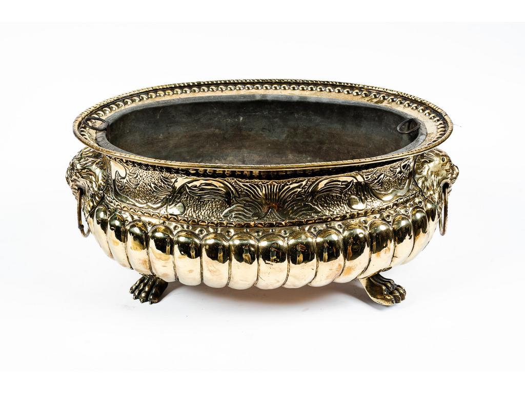 Jardinière dans le goût du XVIIème siècle de forme ovale en laiton repoussé à décor de mufles de lion, godrons, reposant sur quatre pieds griffes. Epoque XIXème siècle. Longueur : 43 cm. (pieds ressoudés)