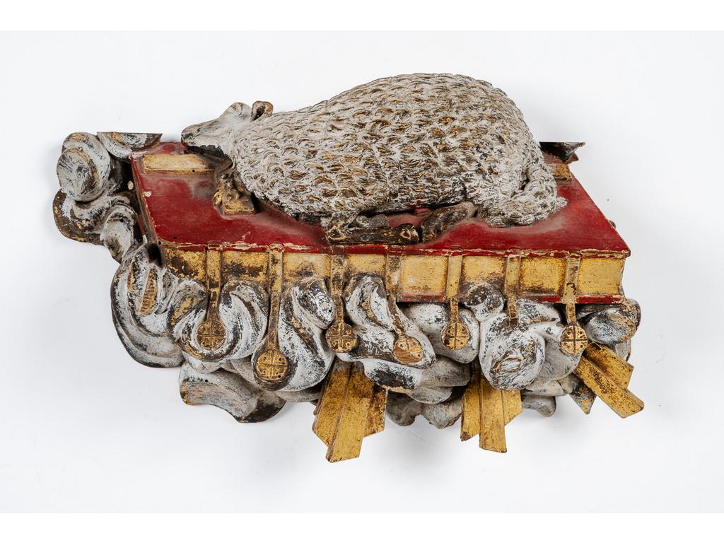 L'Agneau Pascal : Sujet en bois sculpté polychrome et doré représentant l'agneau sacrifié sur un autel au dessus de nuées et rayons de soleil. Longueur : 30 cm. (quelques manques)