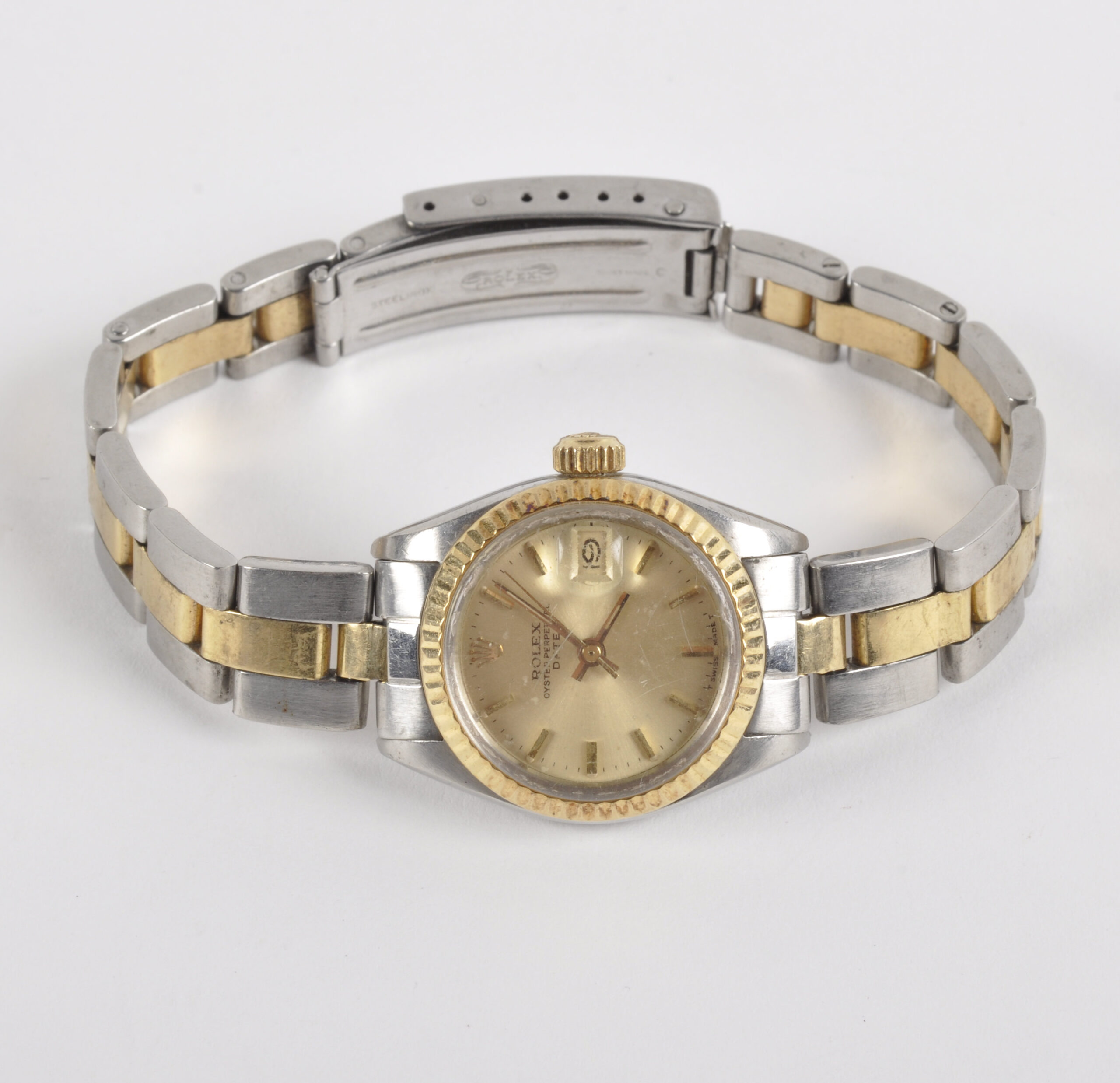 ROLEX, Datejust, ref. 6917, n° 6631106, Vers 1981. Montre-bracelet de dame en acier et or jaune 18k (750). Boîtier rond, lunette en or cannelée, fond vissé, signé. Cadran champagne, index « bâton » appliqués, trotteuse centrale, date à guichet, signé. Mouvement automatique cal. 2030, signé (à réviser). Bracelet Oyster en or et acier, ref. 78343, end links 490. Diam. 26 mm. Poids brut : 55,00 g. RAPPORT DE CONDITION : Veuillez noter que cette montre est vendue en l’état. Le mouvement ne fonctionne pas. Révision à prévoir. Signes d’usure sur le boîtier. Plexiglass rayé, plusieurs marquages d’horlogers dans le fond de boîte. Bracelet détendu, signes d’usure. Révisions et rhabillage recommandés. Veuillez noter que toutes les montres sont vendues en l’état. Aucune garantie sur l’état de fonctionnement. La plupart des montres ont été ouvertes pour identifier le type et la qualité du mouvement, y compris les montres résistantes à l’eau. Il est conseillé à l’acheteur de consulter un horloger pour revoir l’étanchéité de la montre. Les indications données sur l’existence d’une restauration, d’un accident ou sur l’état de préservation restent soumises à l’appréciation personnelle des acquéreurs. L’absence d’indication de pièces de remplacement, d’une restauration ou d’un accident n’implique nullement qu’un bien soit exempt de tout défaut présent. Tous les objets présentés sont susceptibles d’avoir fait l’objet d’un service antérieur et peuvent présenter des pièces non d’origine. Les dimensions et le poids des objets sont renseignés à titre approximatif.