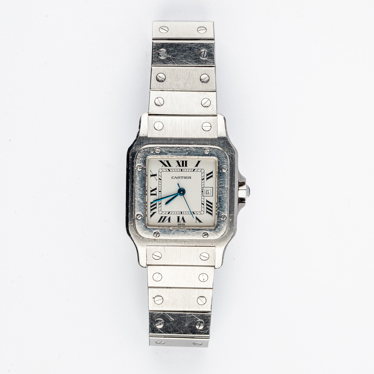 CARTIER : Santos, ref. 2960, n° 01571. Vers 1980. Montre-bracelet en acier, couronne de remontoir ornée d’une pierre facettée, fermeture à vis, signé. Cadran blanc, chiffres romains, trotteuse centrale, date à guichet, signé. Mouvement automatique cal. ETA, signé. Bracelet en acier. Boucle déployante signée. Tour de poignet : approx. 18,5 cm. Dim. 29 x 40 mm. RAPPORT DE CONDITION : Mouvement opérationnel au moment de la rédaction du catalogue. Rayures et griffures d’usage. Cadran en bon état. Révision et rhabillage recommandés. Veuillez noter que toutes les montres sont vendues en l’état. Aucune garantie sur l’état de fonctionnement. La plupart des montres ont été ouvertes pour identifier le type et la qualité du mouvement, y compris les montres résistantes à l’eau. Il est conseillé à l’acheteur de consulter un horloger pour revoir l’étanchéité de la montre. Les indications données sur l’existence d’une restauration, d’un accident ou sur l’état de préservation restent soumises à l’appréciation personnelle des acquéreurs. L’absence d’indication de pièces de remplacement, d’une restauration ou d’un accident n’implique nullement qu’un bien soit exempt de tout défaut présent. Tous les objets présentés sont susceptibles d’avoir fait l’objet d’un service antérieur et peuvent présenter des pièces non d’origine. Les dimensions et le poids des objets sont renseignés à titre approximatif.