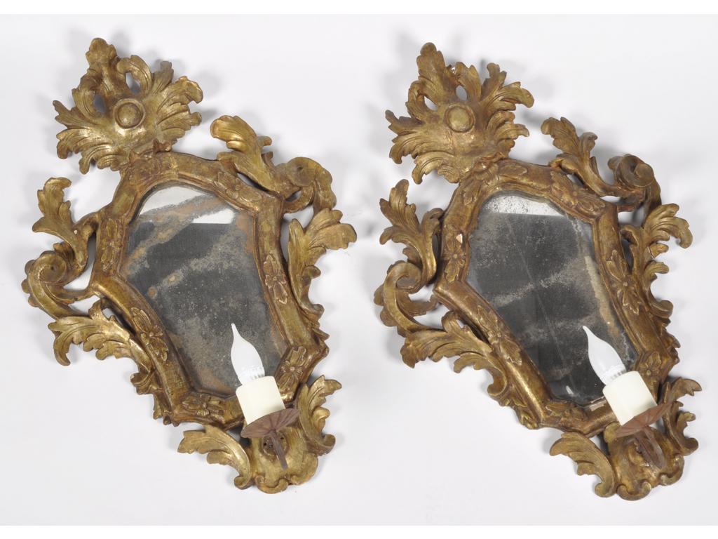Paire de miroirs italiens. Cadre en bois ajouré et doré éclairant à un bras de lumière. Hauteur : 78 cm