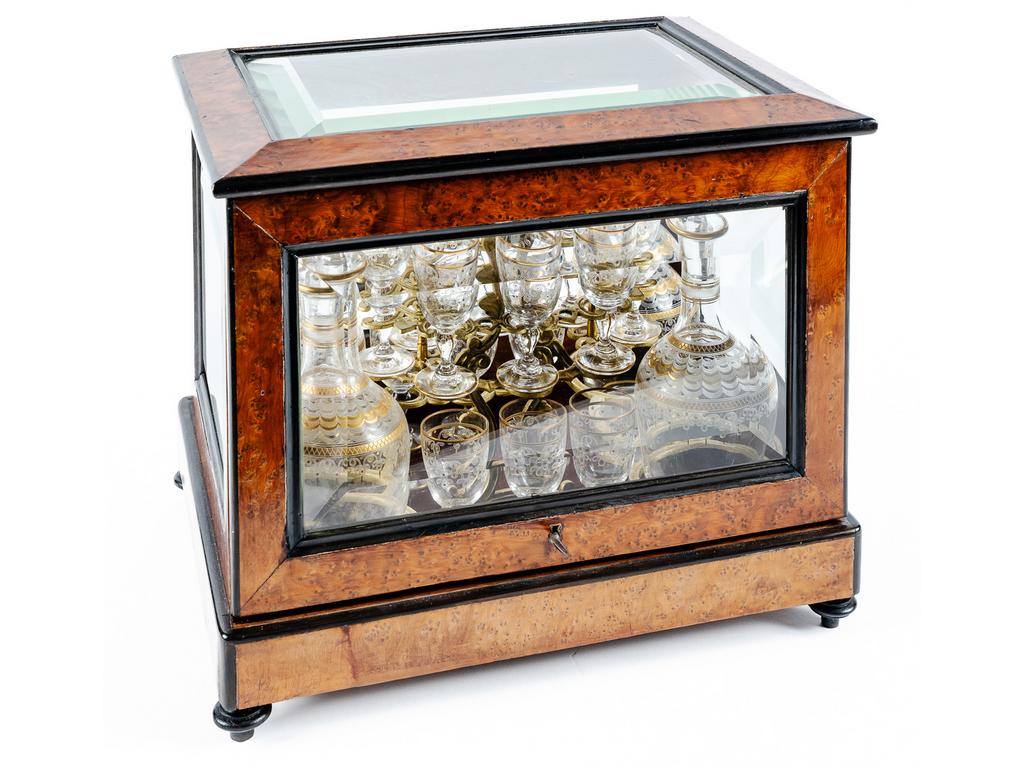 Cave à liqueur en verre biseauté et bois ronceux. A lintérieur : verres et flacons en cristal et rehauts dorés. Epoque XIXe. Dim : 29x34x25xcm (vitre arrière fêlée)