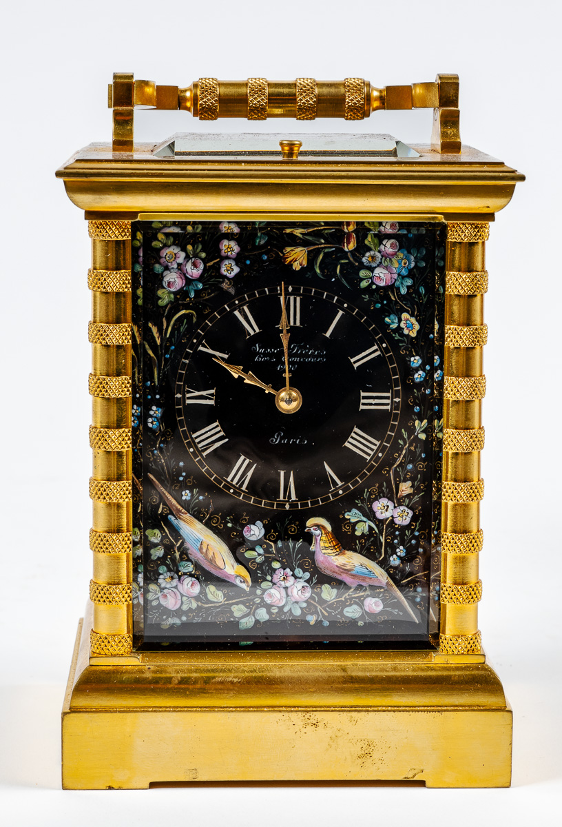 Pendulette de voyage signée SUSSE Frères Hors concours Paris. Cadran émaillé à décor doiseaux et fleurs sur fond noir. Cage en bronze doré. Hauteur : 16 cm