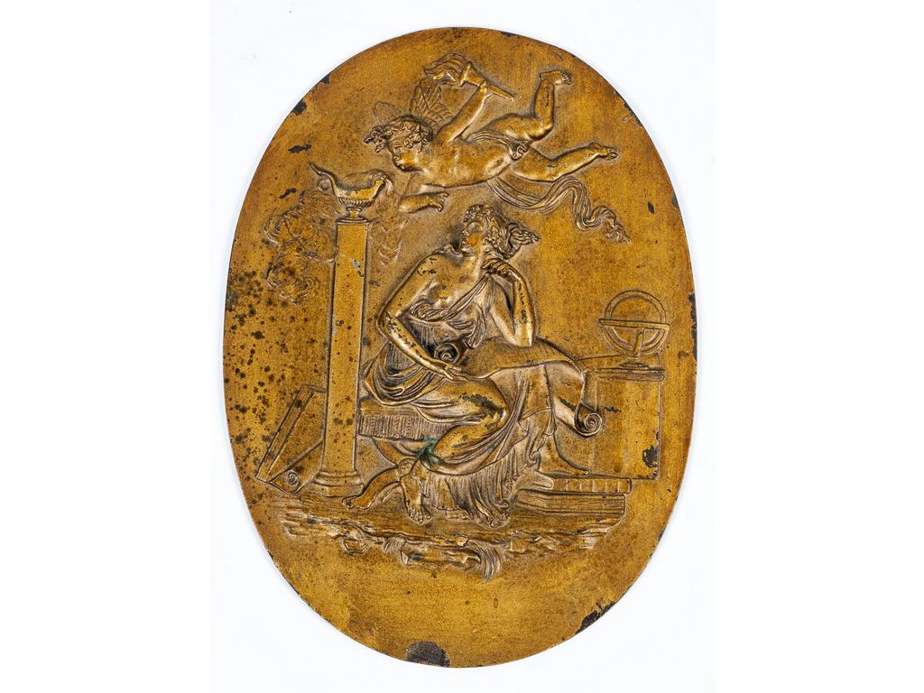 Médaillon ovale en bronze doré à décor en bas relief d'une scène à l'Antique représentant une déesse et Cupidon attisant une le feu d'une lampe à 'huile. Epoque Directoire. (Quelques usures à la dorure). Dim : 19 x 14 cm.