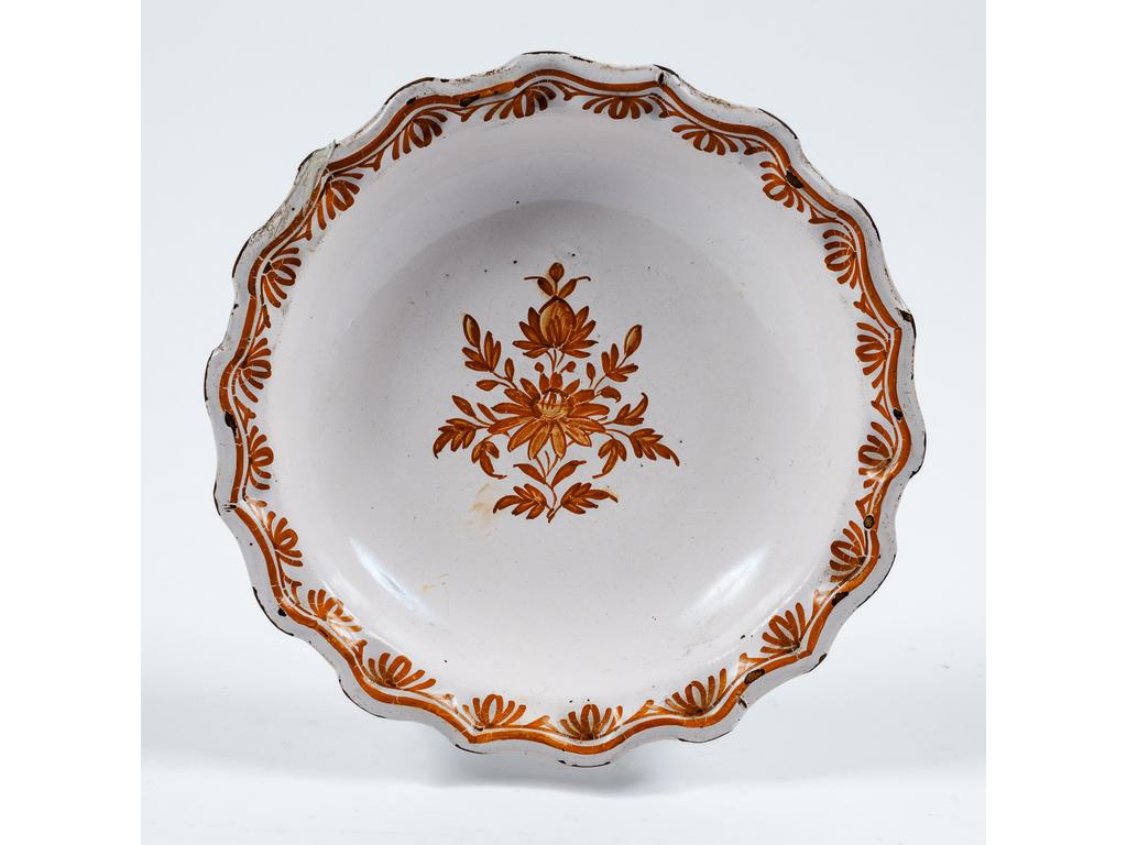 MIDI : Petit plat creux en faïence à bords polylobés et à décor peint au centre d'un bouquet. Epoque fin du XVIIIème siècle. (Eclat au talon, et d'émail sur une aile). Diamètre : 29 cm.