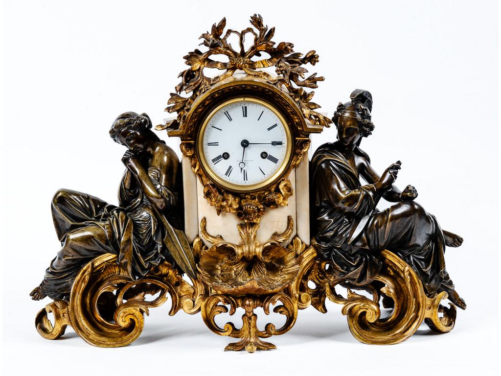 Garniture de cheminée Napoléon III en bronze à deux patines et marbre blanc, comprenant une pendule en forme de fontaine, signée THOMAS, flanquée de deux personnages mythologiques tenants un glaive et une lance. Et une paire de candélabres ornés de putti tenant une corne d'abondance à cinq bras de lumière. Dim de la pendule : 43 x 57 x 20 cm. Dim des candélabres : 55 cm de haut.