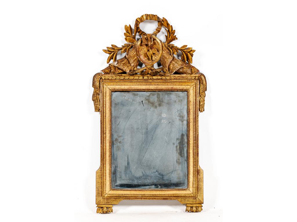 Miroir en bois sculpté et doré d'époque Louis XVI, surmonté d'un fronton à décor d'un couple d'oiseaux dans un médaillon entouré de feuilles de laurier et noeuds de rubans. (Petits manques). Dim : 97 x 55.5 cm.