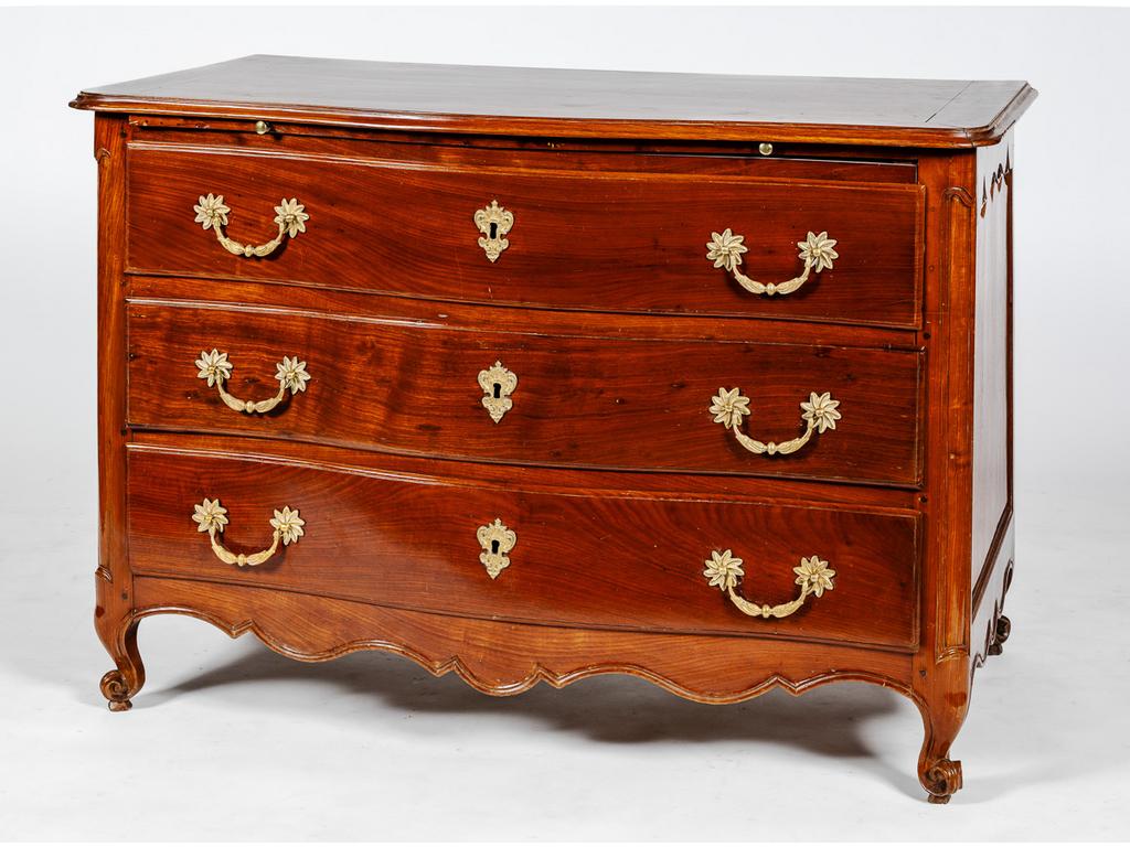 Commode d'époque Louis XV en acajou à façade légèrement galbée, ouvrant par une tirette et trois tiroirs et reposant sur quatre petits pieds cambrés à enroulements. Travail de port du XVIIIème siècle. Entrées de serrure et poignées en bronze doré. Dim : 85 x 125 x 68 cm.