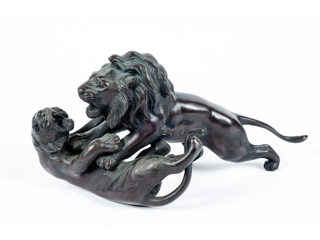 JAPON, Période Meiji : Lion attaquant un tigre. Sujet en bronze patiné, signé d'un cachet. (Usures à la patine du dos du tigre). Dim : 13 x 25.5 x 10 cm.