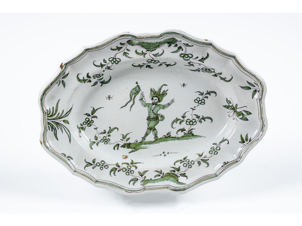 MOUSTIERS : Plat ovale à aile chantournée en faïence de grand feu à décor de grotesques en camaïeu vert. Epoque XVIIIème siècle. (Petits éclats d'émail). Dim : 24 x 33 cm.