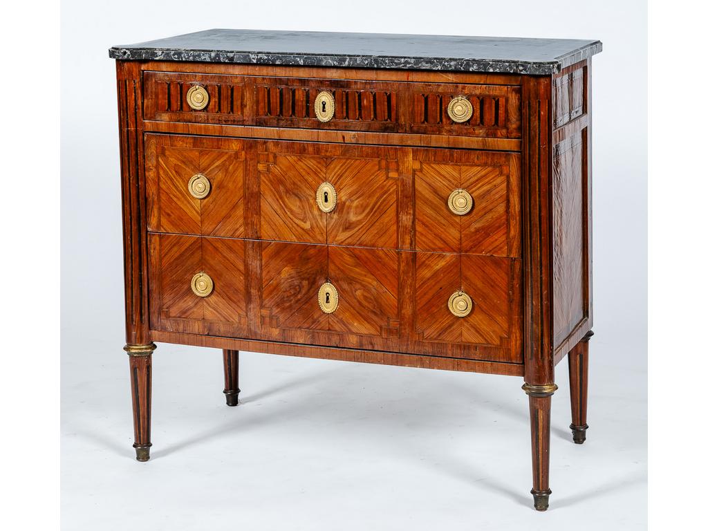 Petite commode d'époque Louis XVI à décor marqueté de fausses cannelures sur les côtés, le tiroir du haut, les montants et les pieds. Elle ouvre par trois tiroirs dont deux sans traverses. Plateau de marbre gris veiné. (Saut de placage). Dim : 86 x 93 x 50 cm.