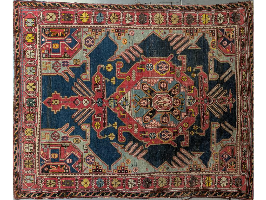 REF 43 /  CAUCASE : Tapis en laine à décor géométrique d'un médaillon sur fond bleu. (Bordures usées). Dim : 167 x 142 cm.