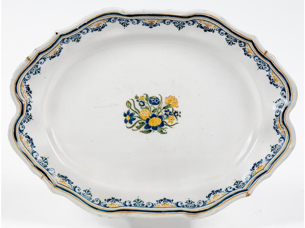MOUSTIERS, XVIIIème siècle : Plat oblong à décor polychrome de solanacées au centre, ailes ornées d'une frise. Signé du monogramme de OLERIS-DELEGLISE. (Petits éclats en bordure). Dim : 28 x 38.5 cm.