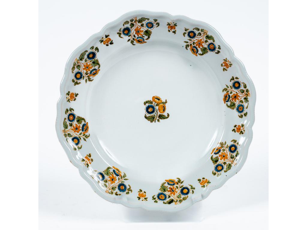 MOUSTIERS, GUYOT : Assiette en faïence à décor polychrome de fleurs de solanacées. Epoque XVIIIème siècle. Signée. Diamètre : 25 cm.