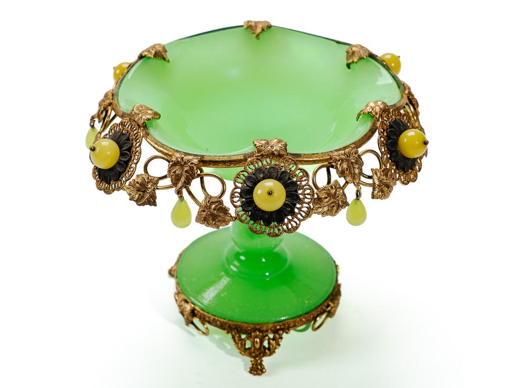 Petite coupelle sur pied en opaline verte sur une monture en laiton et tôle dorée à décor de fleurs et petites pampilles en opaline. (Altération et maladie du verre). Hauteur : 12 cm.