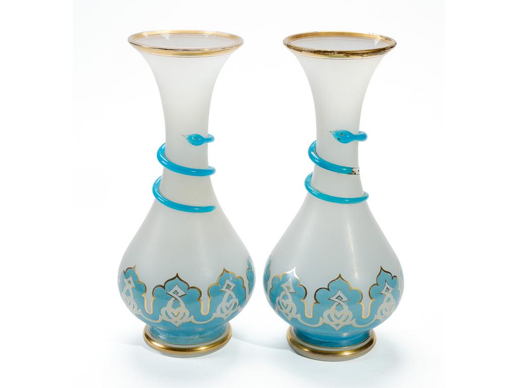 Paire de vases balustres en opaline blanche. Les bases à décor peint d'arabesques dorées sur fond bleu turquoise et les cols ornés d'un serpent. (Un serpent cassé avec manques et usures de dorure sur les cols). Hauteur : 30 cm.