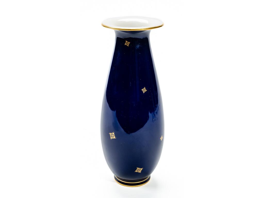 SEVRES : Petit vase en porcelaine gros bleu à décor de petites fleurs dorées, le col et le pied surlignés de liserés dorés. Signé. Epoque XXème siècle. Bon état. Hauteur : 23 cm.
