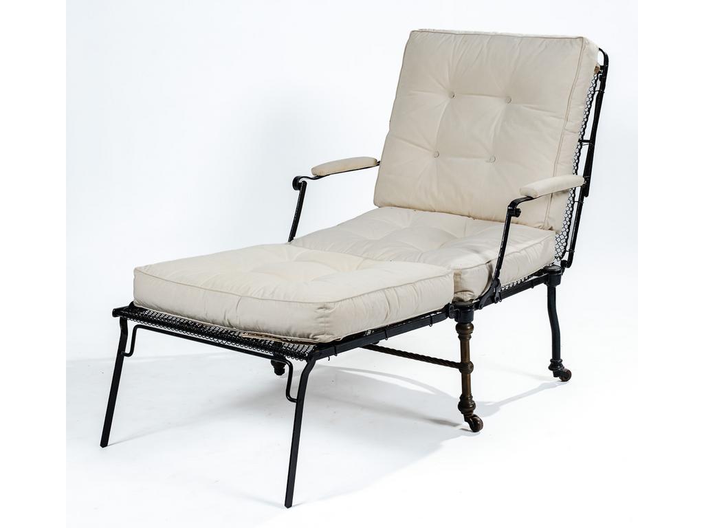 Chaise longue pliante de jardin, en métal laqué noir, formant bergère et reposant sur des pieds antérieurs de forme balustre. Assise garnie de coussin en tissu. Travail anglais vers 1900, édité par W.S. Patent. (Petit accidents au treillage de l'assise).