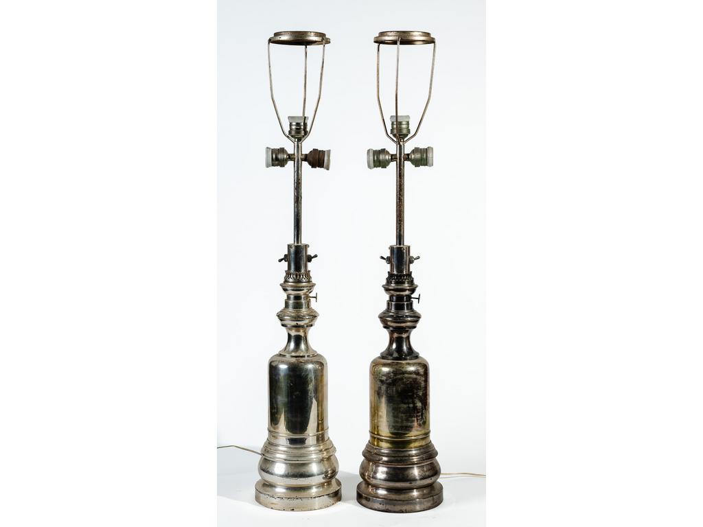 Paire de lampes à pétrole en métal argenté montées à l'électricité (sans globe ni tulipe, usure à l'argenture). Hauteur totale : 89 cm