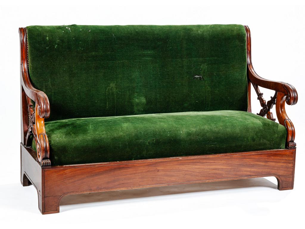Canapé d'époque Restauration en acajou et placage d'acajou flanqué d'accotoirs ajourés à motif de croisillons. Garniture de velours vert. (Déchirures, tâches et petits sauts de placage). Dim : 91 x 146.5 x 62 cm.