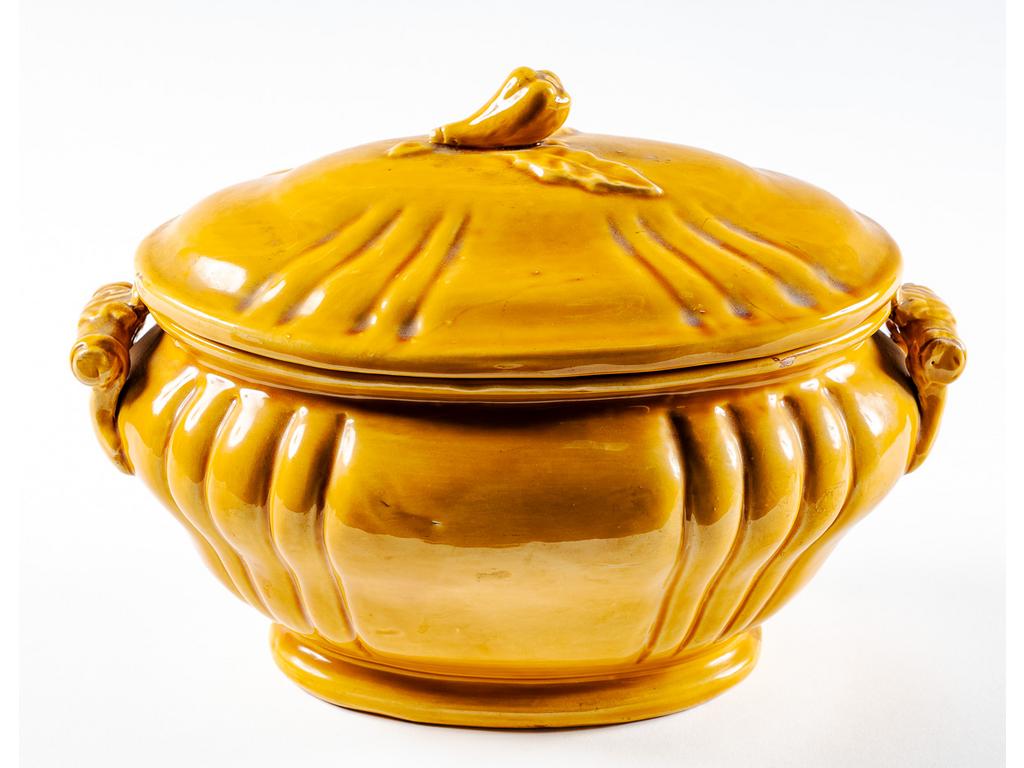 Manufacture PICHON à Uzès : Légumier à anses en faïence émaillée ocre surmonté d'un couvercle à fretel en forme de légume. Signé du cachet de Bernard PICHON. (Infimes fêles de cuisson au talon). Dimensions : 21,5 x 29 x 18 cm.