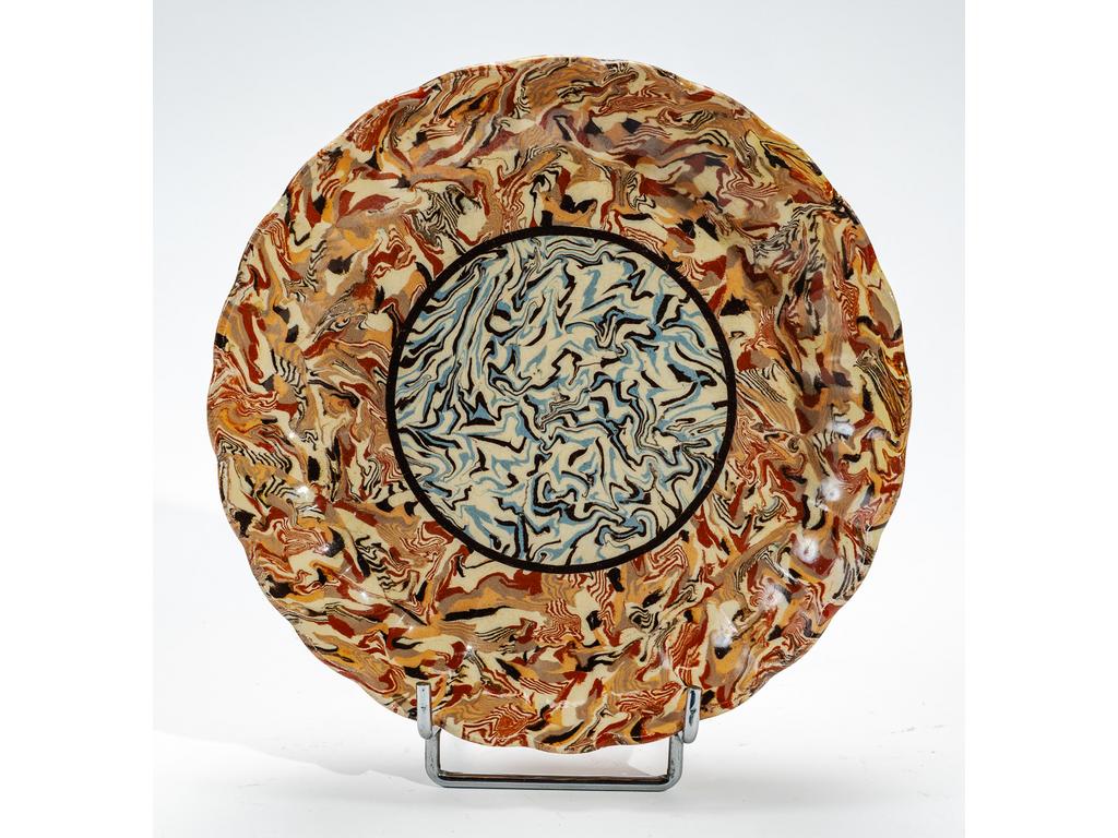 Manufacture PICHON à Uzès : Plat creux à aile chantournée orné d'une rosace sur fond marbré en terres mêlées. Signé du cachet de Bernard PICHON. (Un petit éclat sur l'aile et sur le talon). Diamètre : 22,5 cm.