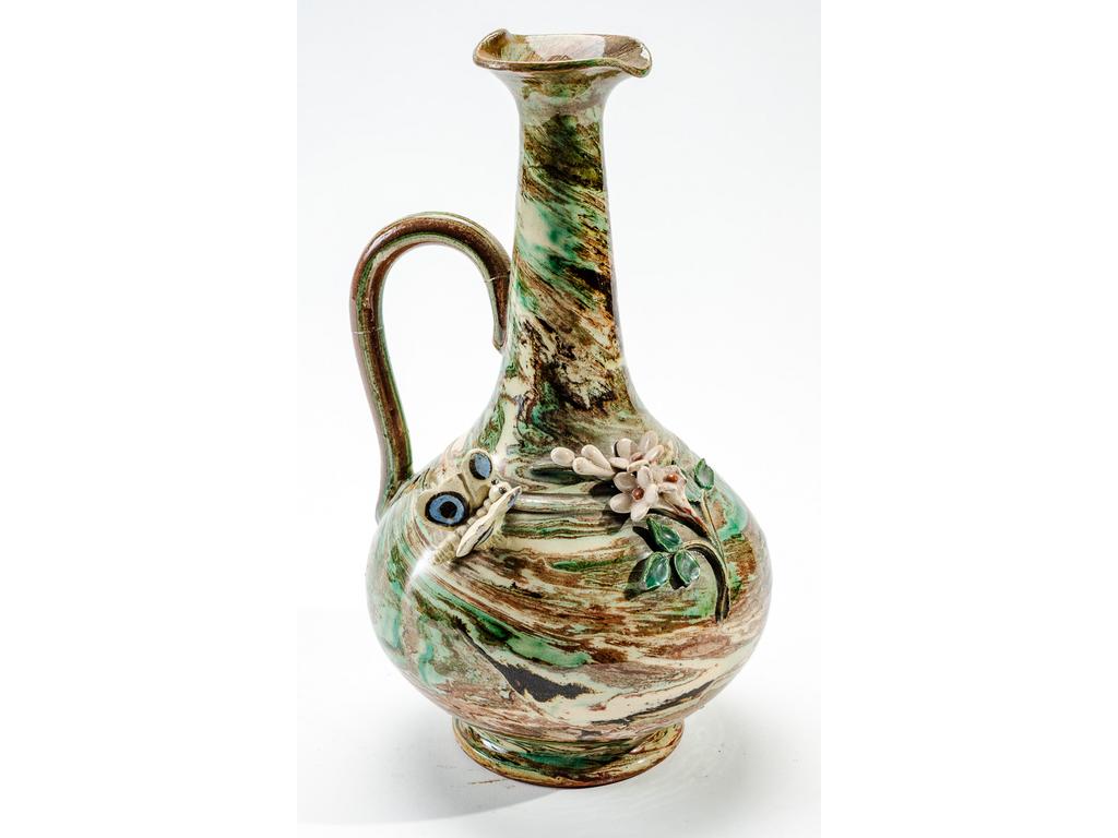 Manufacture PICHON à Uzès :  Pichet en céramique à décor, en relief, de fleurs et papillon sur fond marbré en terres mêlées. (Petits éclats et anse cassée, recollée). Hauteur : 26,5 cm.