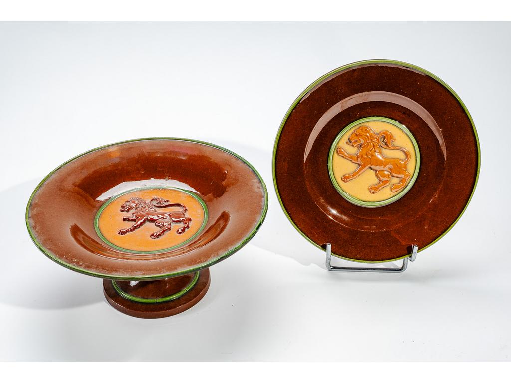 Manufacture PICHON à Uzès :  Une assiette (diamètre : 20,5 cm) et une coupe sur piédouche (hauteur : 10 cm et diamètre : 23 cm) en faïence polychrome à décor en léger relief d'un lion. Signées du cachet de François PICHON. (Manque et fêles de cuisson à la coupe).