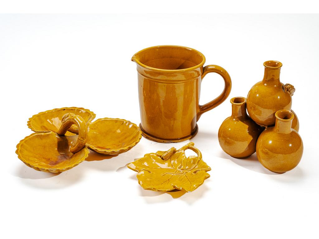 Manufacture PICHON à Uzès : Ensemble de pièces en faïence émaillée ocre comprenant : un broc (éclats à la base. Hauteur : 17 cm), un pique-fleurs composé de quatre vases globulaires à cols étranglés et à décor, en relief, d'une cigale (éclats au col. Hauteur : 20 cm), un plat mendiant composé de trois coquilles (cassé, recollé) et une coupe en forme de feuille de vigne à décor, en relief, d'une cigale (petits éclats. Dimensions : 3 x 17,5 x 14,5 cm). Signées du cachet.