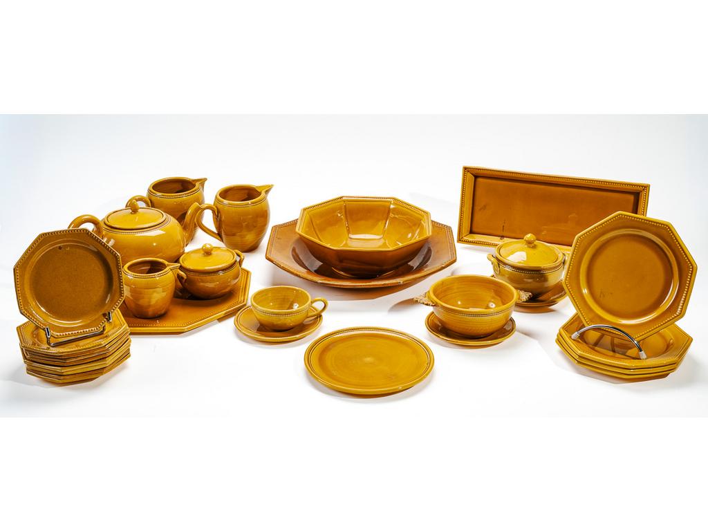 Manufacture PICHON à Uzès : Partie de service de table en faïence émaillée ocre à décor de rais de perles comprenant : un plat à cake, un saladier, un plat creux, un plat à gâteau, un bouillon à oreilles (une anse cassée), quatre petites assiettes, neuf assiettes à entremets, une petite assiette circulaire, une tasse et trois sous-tasses, une théière, trois petites verseuses (éclats aux becs), et deux pots à crème (un éclat à un couvercle). Signés du cachet.