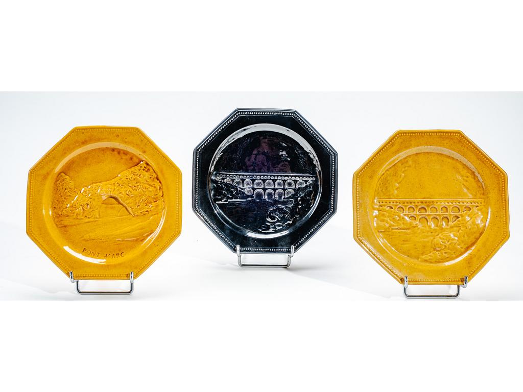 Manufacture PICHON à Uzès : Trois assiettes octogonales en faïence émaillée représentant, en léger relief, Pont d'Arc et le Pont du Gard. Signées du cachet de Bernard PICHON. Diamètres : 23,5 cm chacune.