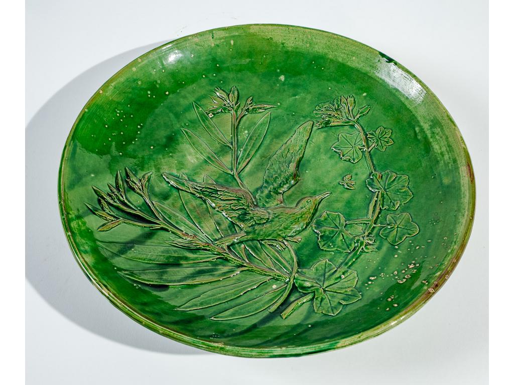 Manufacture PICHON à Uzès : Grand plat circulaire en terre cuite émaillée vert à décor, en léger relief, d'un oiseau branché. Signé du cachet de Bernard PICHON. (Petits défauts d'émaillage). Diamètre : 38 cm.