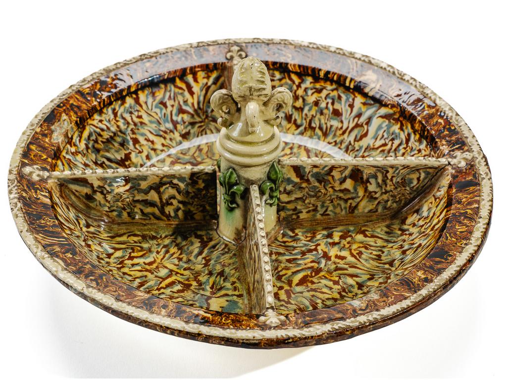 Manufacture PICHON à Uzès : Plat à crudités ou mendiant à décor marbré en terres mêlées et orné d'un fretel en forme de fleur de lys. (Fêles de cuisson et petit défaut au talon). Diamètre : 26 cm.