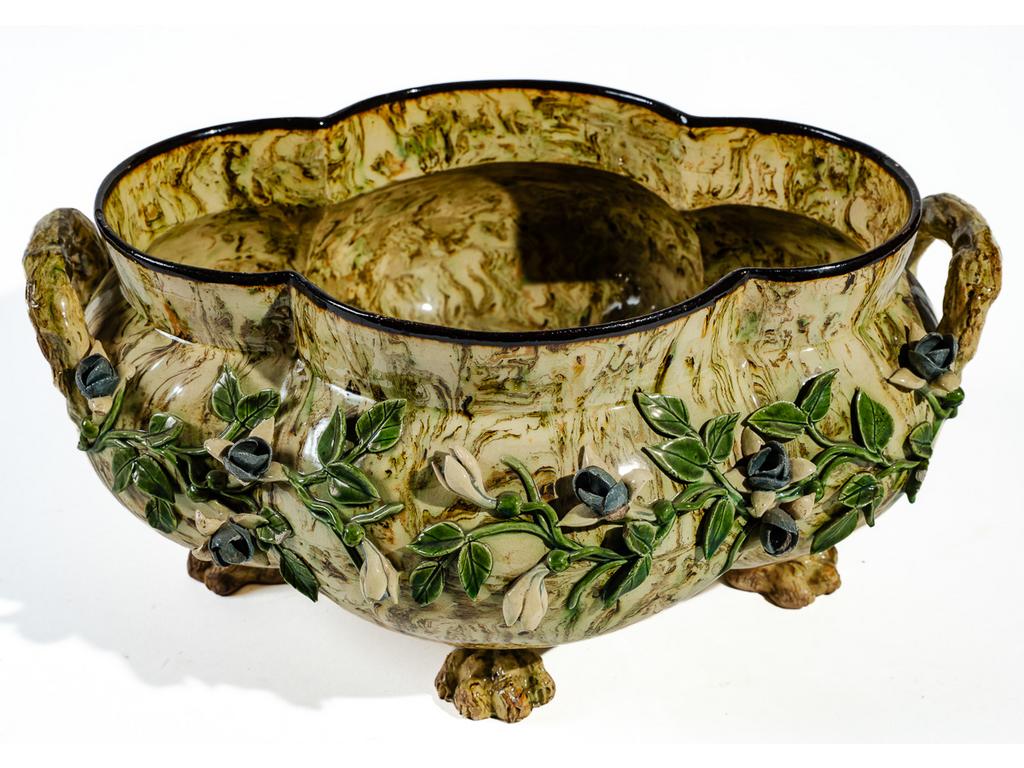 Manufacture PICHON à Uzès : Jardinière de table polylobée à anses, reposant sur quatre pieds griffes de lion et à décor, en relief, de fleurs et feuillages sur fond marbré en terres mêlées. Signée du cachet de François PICHON. (Petits manques et accidents au feuillage). Dimensions : 18 x 37 x 30 cm.