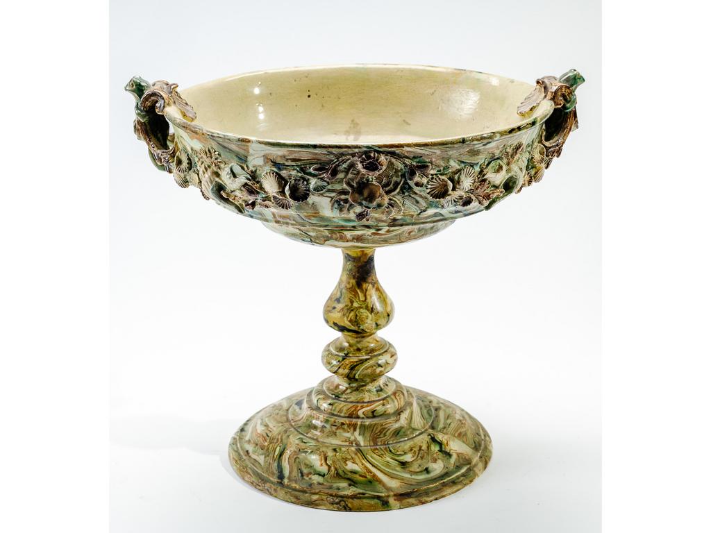 Manufacture PICHON à Uzès : Grande coupe à anses sur piédouche en faïence à décor, en relief, de coquillages, crustacés et batraciens dans le goût de Palissy sur fond marbré en terres mêlées. (Pied cassé, recollé et fêles). Hauteur : 28 cm. Diamètre : 34 cm.