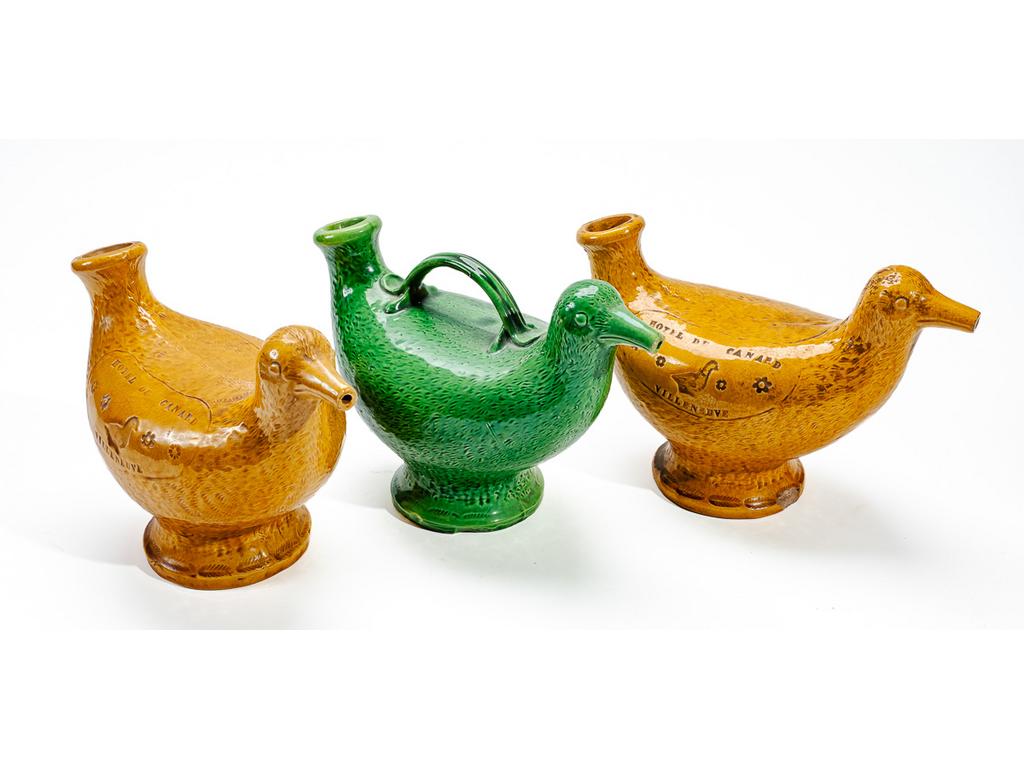 Manufacture PICHON à Uzès : Trois verseuses zoomorphes en faïence en forme d'oiseaux, dont deux à l'enseigne de lHôtel du Canard à Villeneuve. Signées du cachet de Bernard PICHON. (Deux avec éclat au pied, sans les bouchons). Dimensions : 16 x 25 x 12 cm.