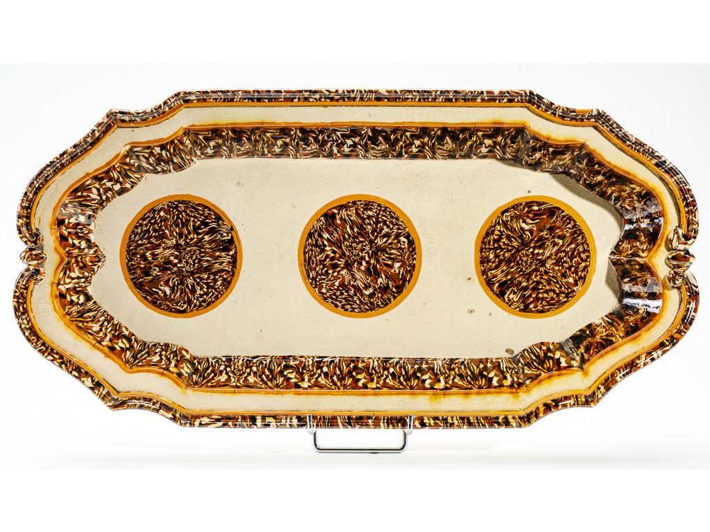 Manufacture PICHON à Uzès : Grand plat ovale en céramique à aile chantournée et à décor de rosaces marbrées en terres mêlées dans des réserves. Signé du cachet de François PICHON. (Fêles de cuisson). Dimensions : 59 x 30 cm.