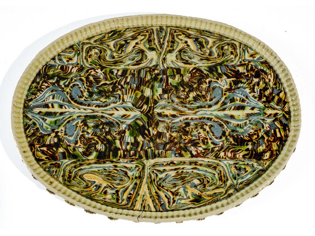 Manufacture PICHON à Uzès : Plat ovale à décor marbré en terres mêlées de fleurs de lys stylisées. Aile cannelée soulignée de fleurettes en léger relief. (Fêles de cuisson). Dimensions : 36 x 27 cm.