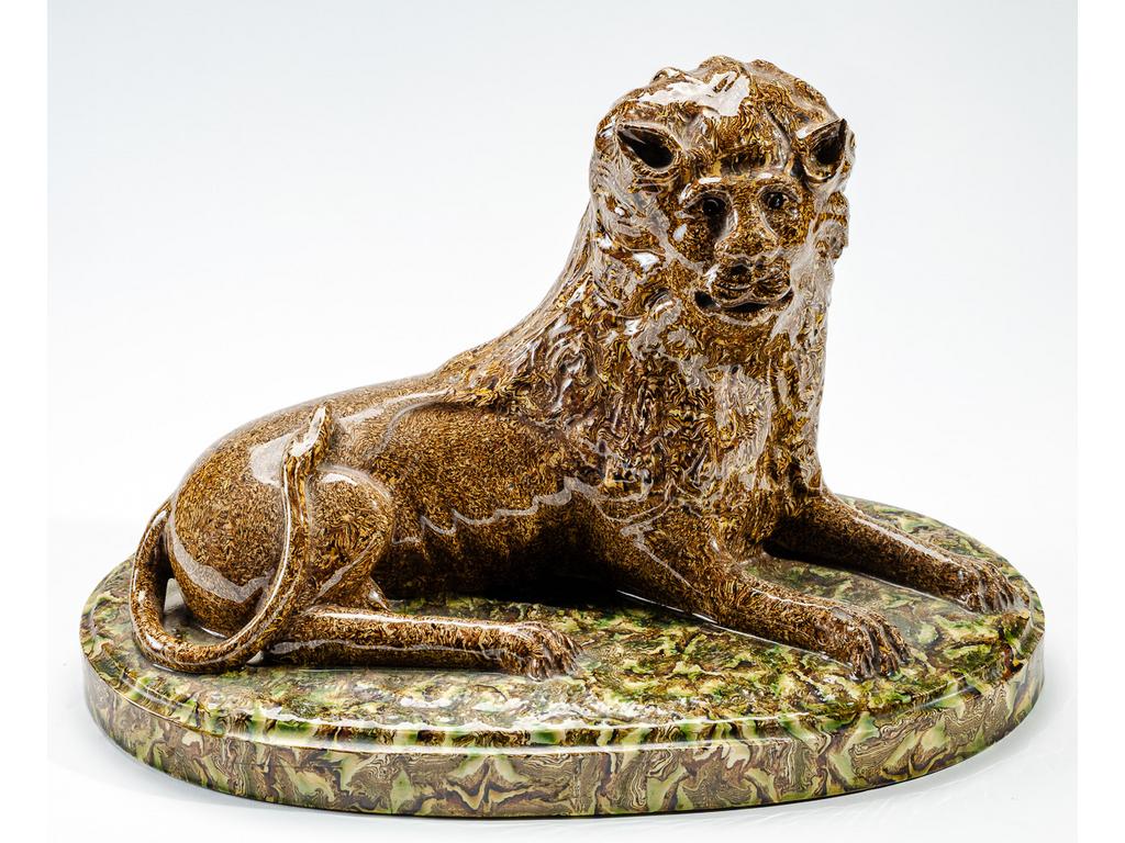 Manufacture PICHON à Uzès : Lion couché marbré en terres mêlées reposant sur une terrasse. Dimensions : 25 x 38,5 x 23 cm.