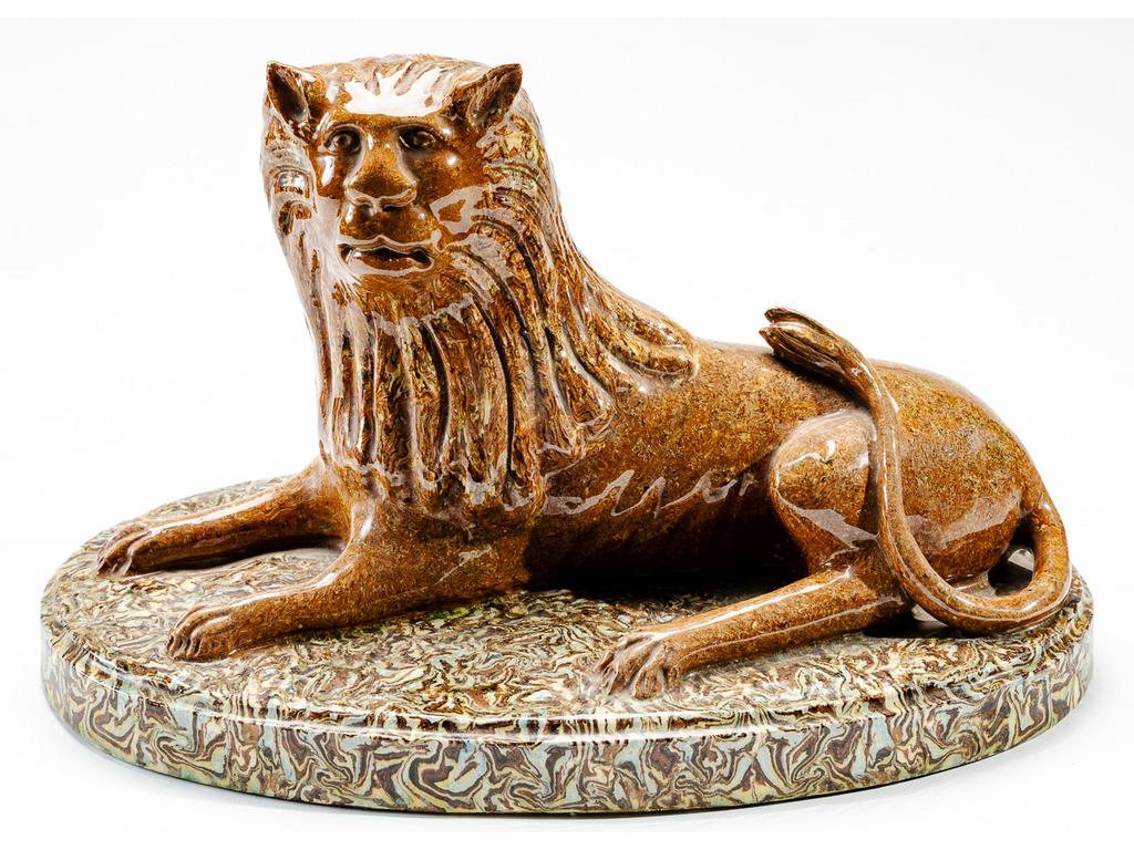Manufacture PICHON à Uzès : Lion couché marbré en terres mêlées reposant sur une terrasse. Dimensions : 22,5 x 38,5 x 23,5 cm.
