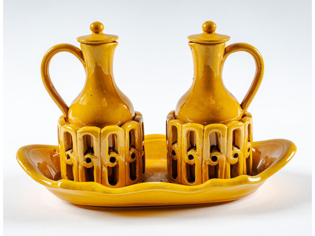 Manufacture PICHON à Uzès : Porte huilier-vinaigrier en faïence ajourée et émaillée ocre avec ses deux burettes. Signé du cachet de Bernard PICHON. (Accidents aux couvercles). Dimensions : 16 x 25 x 13,5 cm.