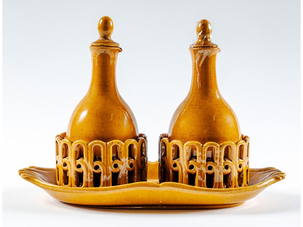 Manufacture PICHON à Uzès : Porte huilier-vinaigrier en faïence ajourée et émaillée ocre avec ses deux burettes. Signé du cachet de Bernard PICHON. (Accidents aux couvercles et un éclat au socle). Dimensions : 21 x 30 x 14,5 cm.