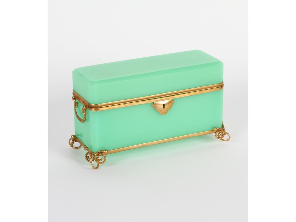 Long coffret de forme rectangulaire en opaline verte sur une monture en laiton et tôle dorée. (Bon état général, à signaler un défaut de cuisson sur le couvercle, sans la clé). Hauteur : 13 cm. Longueur : 21 cm.