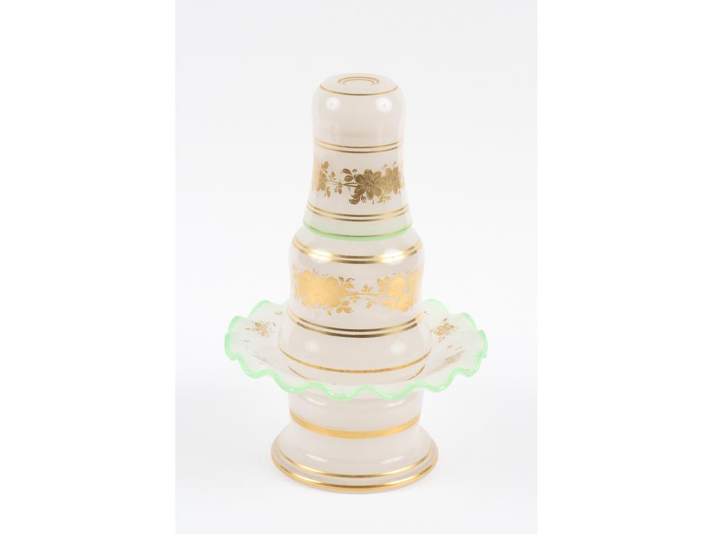 Verre de nuit en opaline blanche et dorée surligné de liserés verts. (Petit éclat au couvercle du flacon). Hauteur : 29 cm.