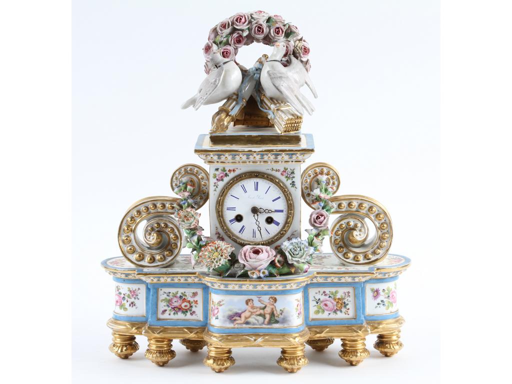 Pendule en porcelaine blanche de style Louis XVI ornée d'un très riche décor peint de fleurs et d'angelots. Le centre et le sommet à décor d'une guirlande de fleurs et d'un couple de colombes. Le cadran signé Jacob PETIT à Paris. Hauteur : 40 cm. (Bon état général, à signaler quelques accidents aux fleurs, et absence de balancier)