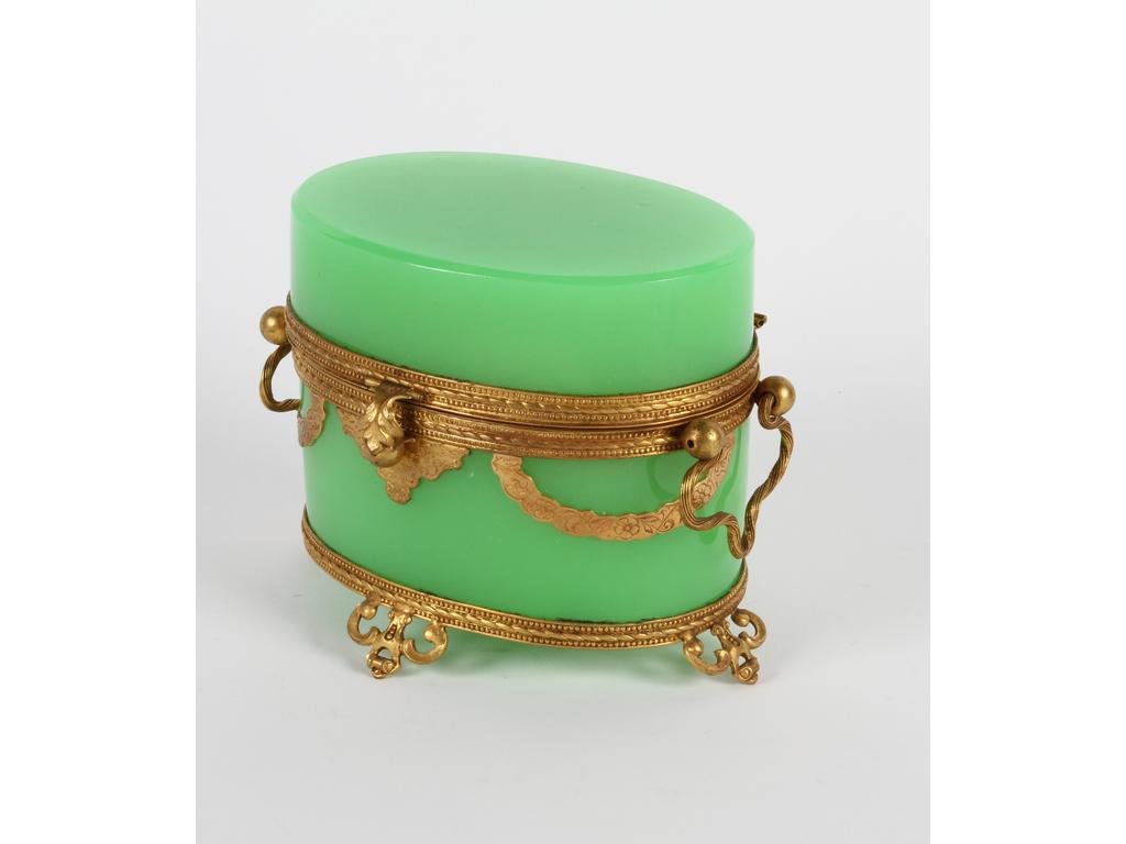 Coffret à senteurs de forme ovale en opaline verte sur une monture en laiton et tôle dorée. A l'intérieur, deux petits flacons en opaline verte et étoiles dorées. (Bon état général, usures aux étoiles dorées) Hauteur : 11 cm.
