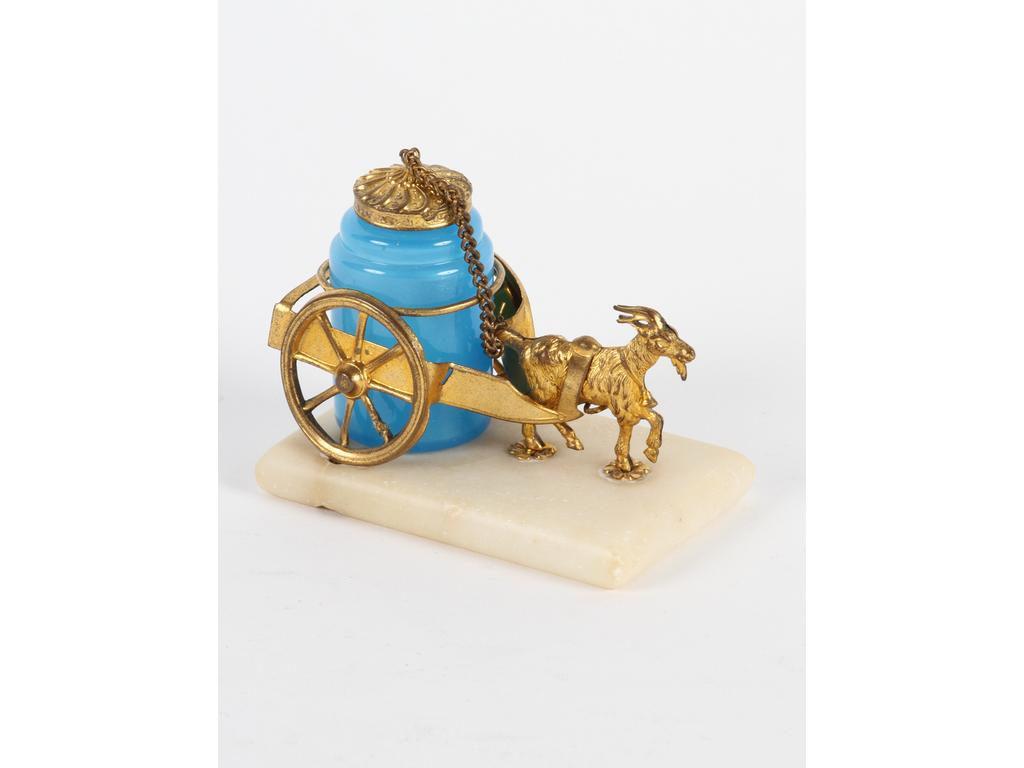 Petit flacon en opaline bleue sur un attelage en tôle dorée tiré par un bouc. Socle en marbre blanc. Bon état. Longueur : 8.5 cm Hauteur : 7 cm.