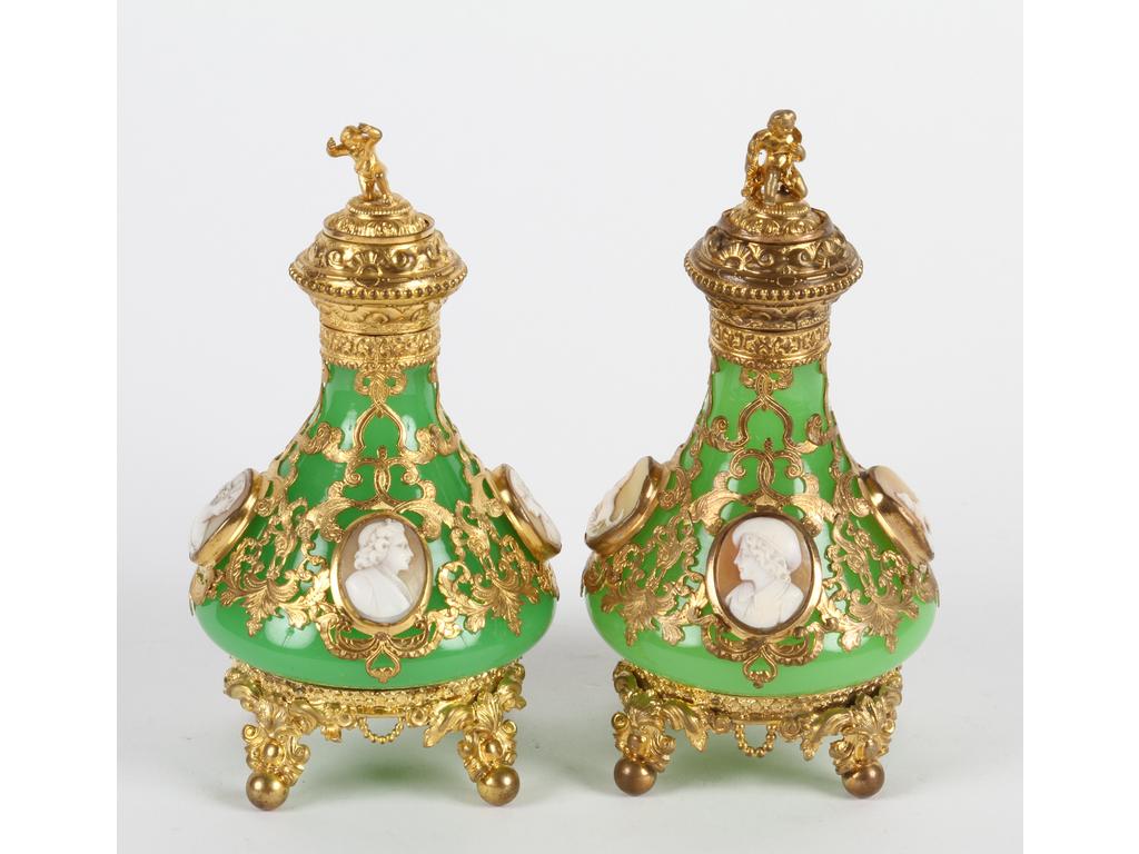 Paire de flacons en opaline verte entièrement enrichis d'une monture en laiton et tôle dorée et ornés chacun de quatre camées sur coquillage. Hauteur : 16 cm. Bon état. (Manques les petits bouchons en verre sous les couvercles).