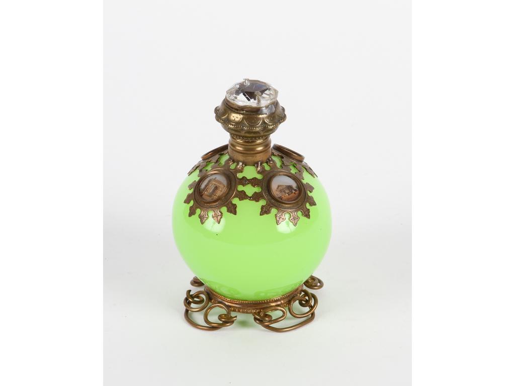 Flacon en forme de boule en opaline verte orné d'une monture en laiton et tôle à décor de quatre petits médaillons lithographiés de monuments parisiens. Bon état. Hauteur : 12 cm